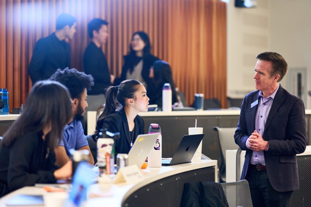 Foster School of Business Associate Dean Dan Turner chats with students before the judges announce the final results.